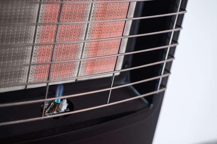 A child sits by the window next to a central heating panel