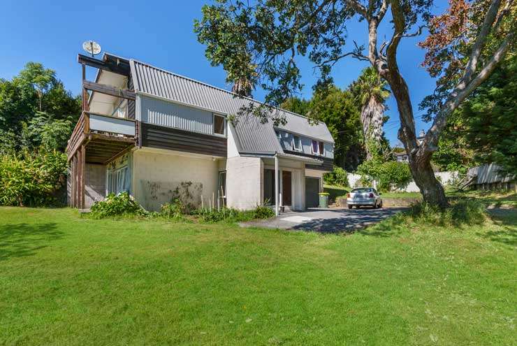 White bungalow house with high fence and greenery 54 Codrington Crescent, Mission Bay, Auckland