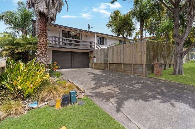 50A waiatarua Road remuera  1950s brick house with red door and sofas on front porch lit up at night