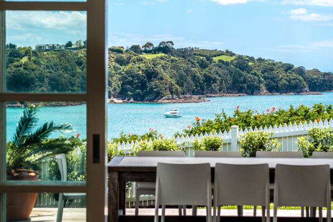 345 Gordons Road, Waiheke Island, Auckland. Grey roofed modern house with deck and lawn overlooking ocean.