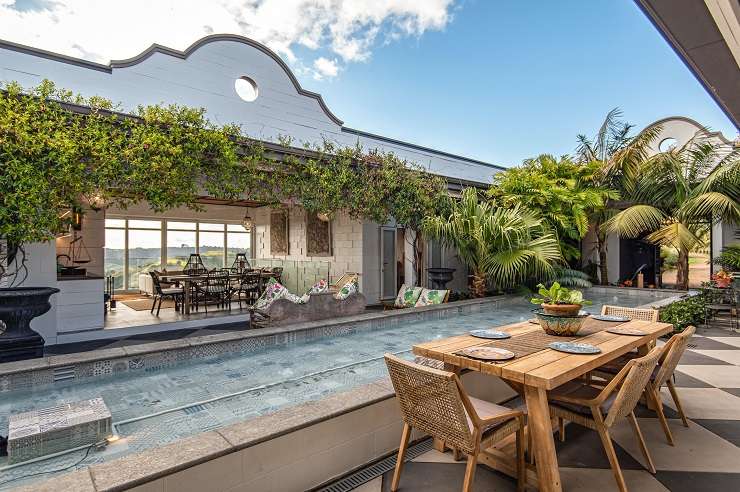 345 Gordons Road, Waiheke Island, Auckland. Grey roofed modern house with deck and lawn overlooking ocean.