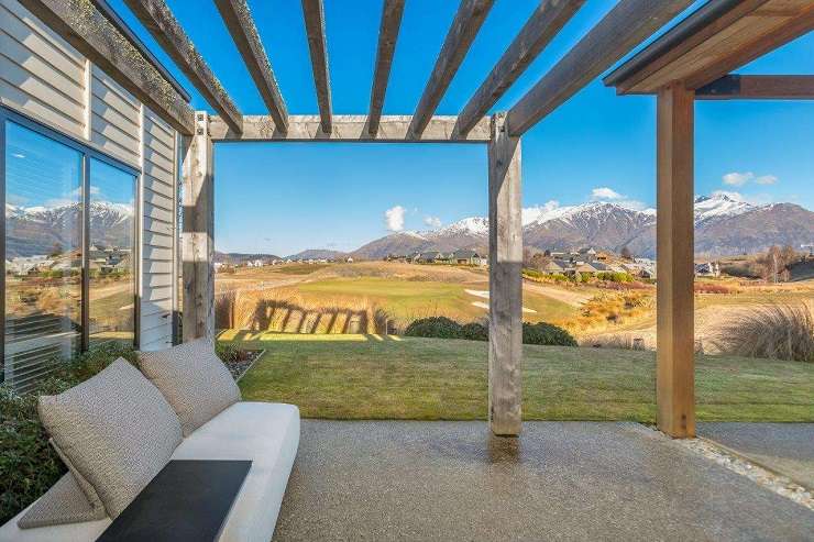 guy pushing golf cart in front of modern black house  210 Oceanbeach Road, MOunt Maunganui