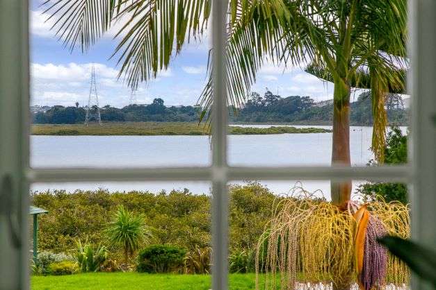 White bay fronted villa with garage doors downstairs and palm tree   177A Avondale Road, Avondale, Auckland