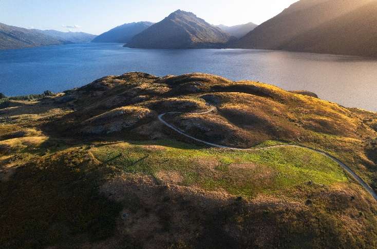 The strip of flat rural land that Queenstown officials are weighing up rezoning can be seen in the centre of the pic, with Lake Hayes in the foreground and lake Wakatipu in the background. Photo / Getty Images