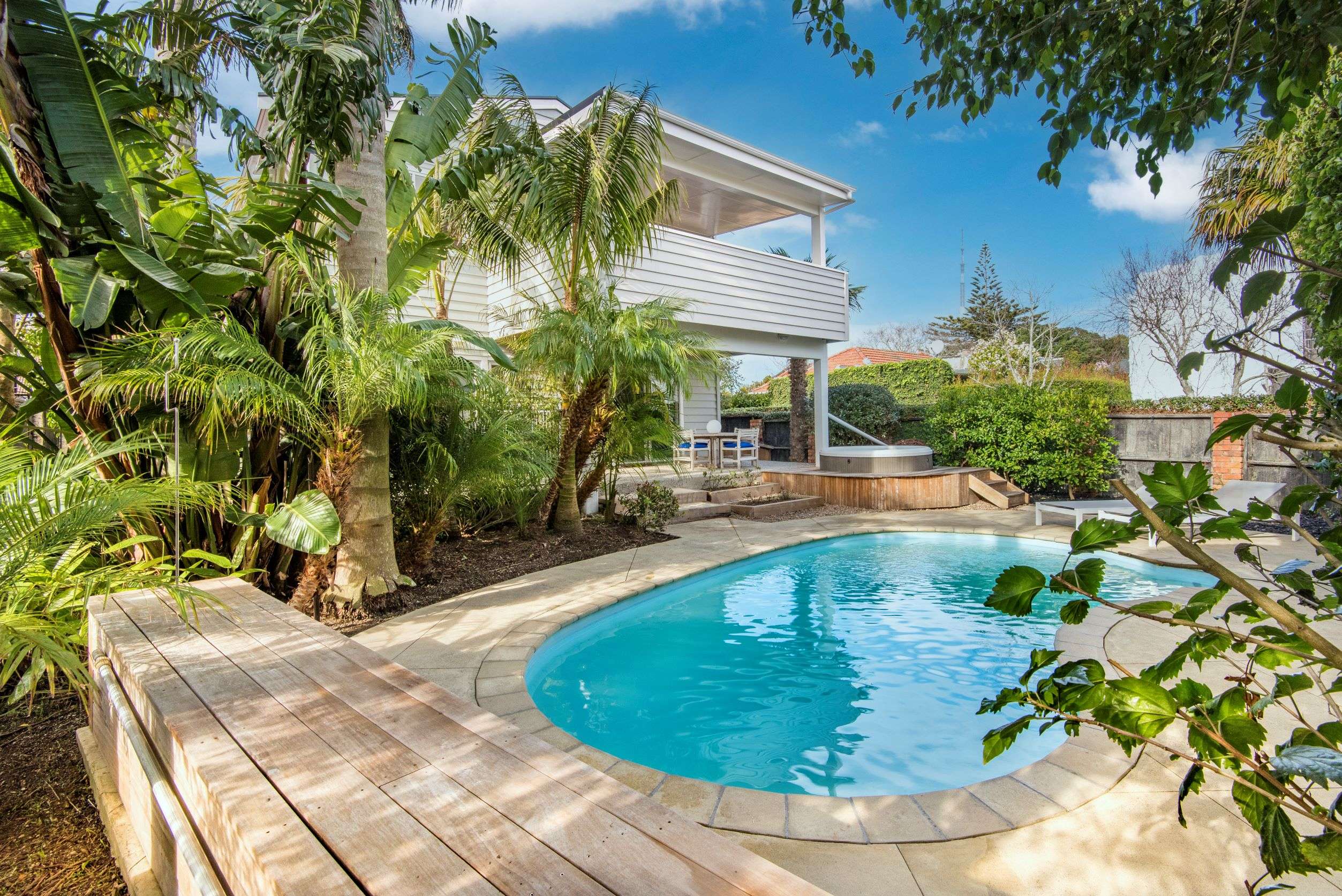 white two-storey house with pool in tropical setting