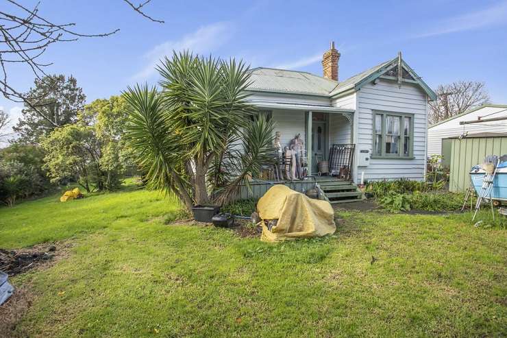 run down house with car and gravel driveway