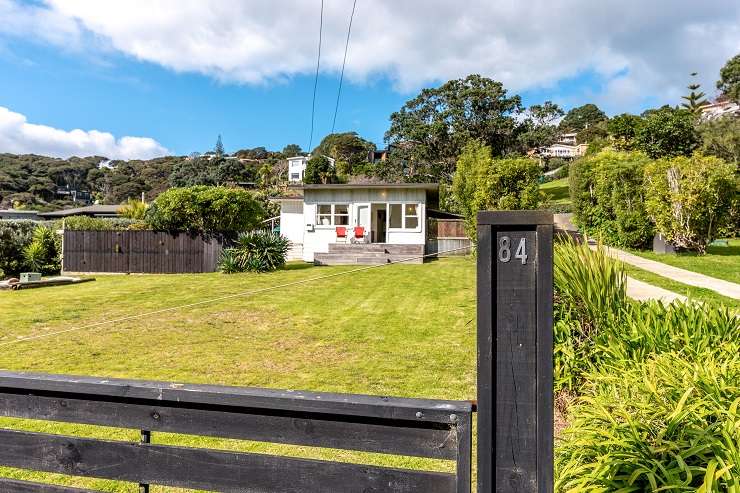 345 Gordons Road, Waiheke Island, Auckland. Grey roofed modern house with deck and lawn overlooking ocean.