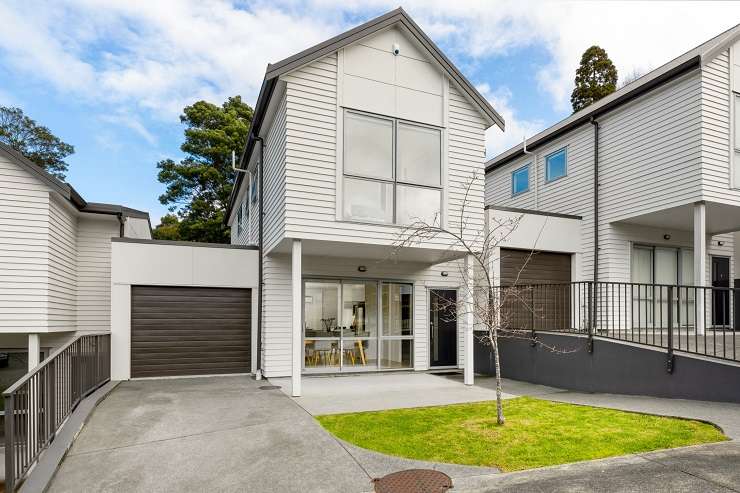 White bay fronted villa with garage doors downstairs and palm tree   177A Avondale Road, Avondale, Auckland