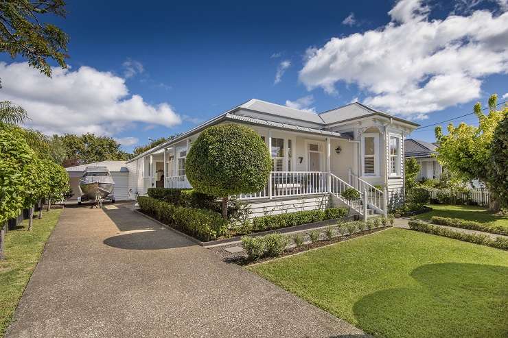 Cream house with grey roof on spreading lawn with swimming pool 51 Maungakiekie Avenue Mount Eden